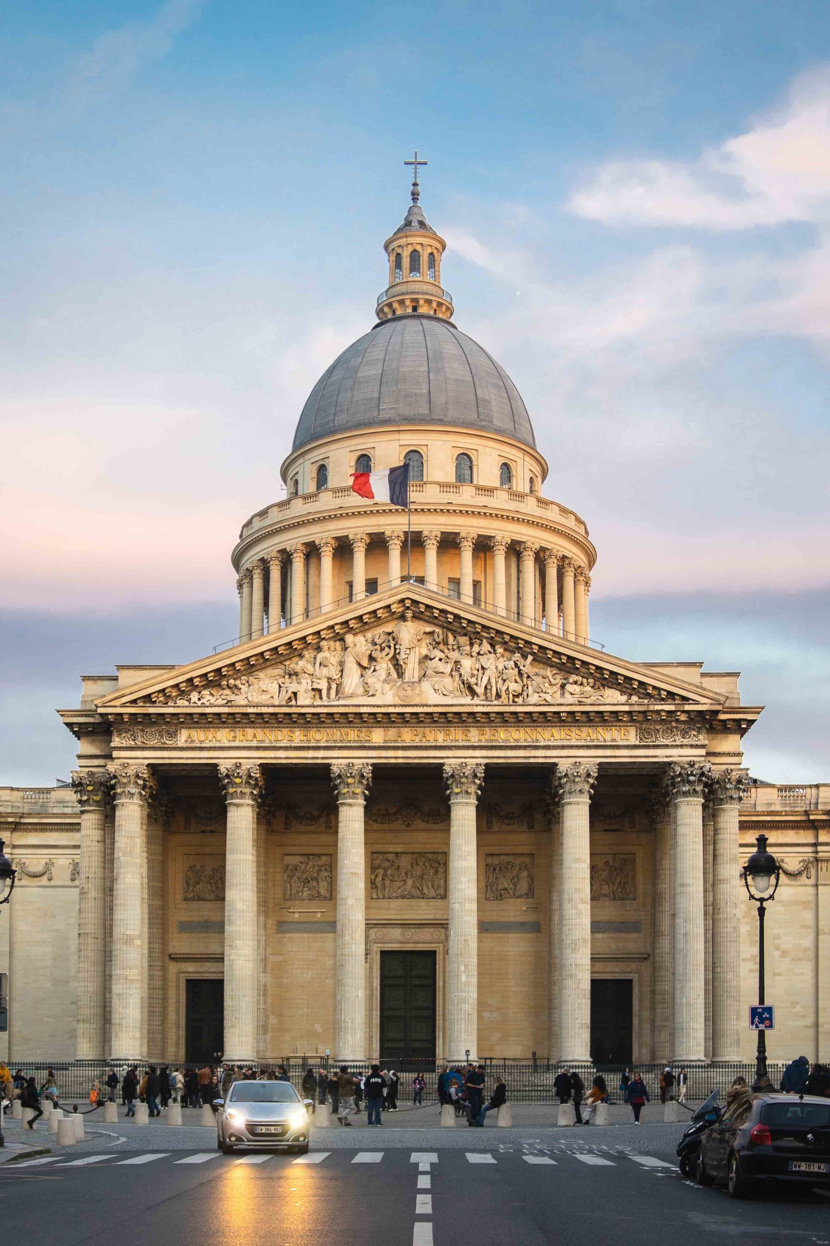 Pantheon surrounded by people under a cloudy sky during sunset in Paris in France
